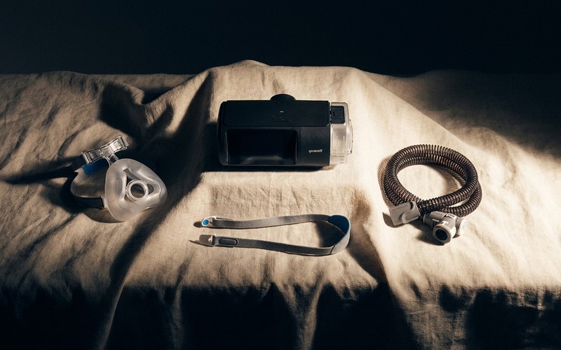 A Yuwell CPAP machine, mask, headgear strap and hose laid out on a bed, showing everything included in the box.