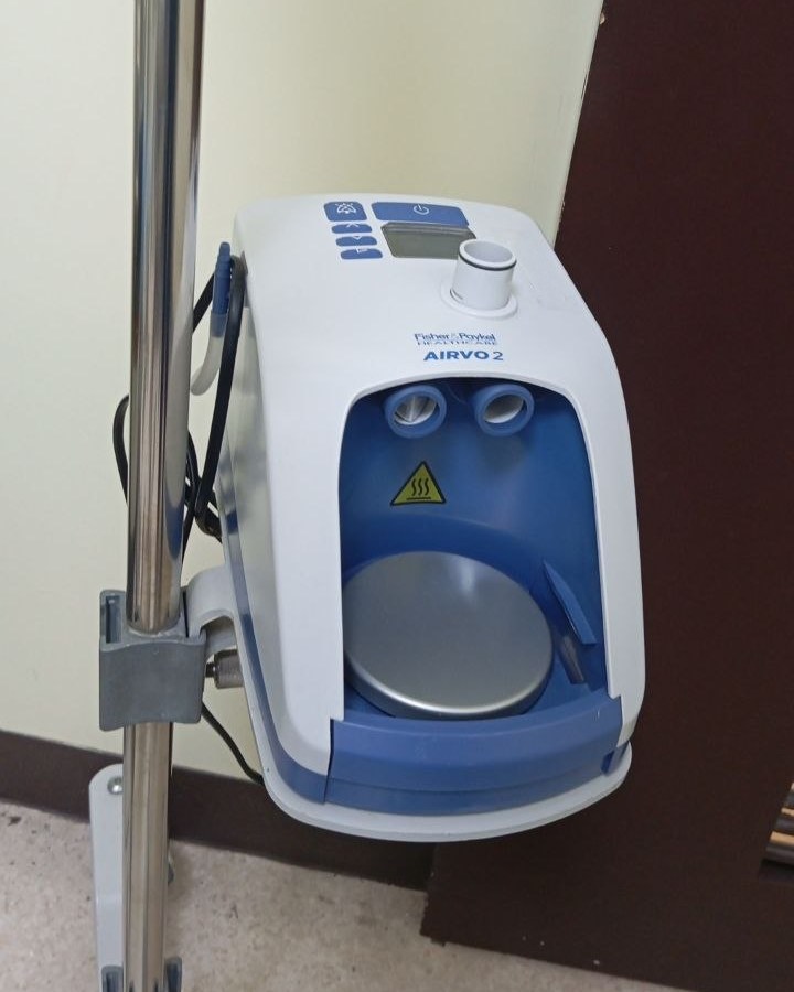 Fisher & Paykel AIRVO 2 humidifier on a pole mount, seen from the front with the heater plate visible.