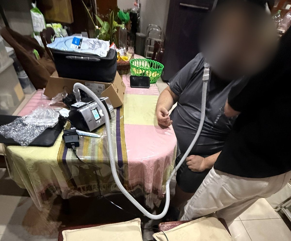 A respiratory therapist fitting the BiPAP mask on the patient at home